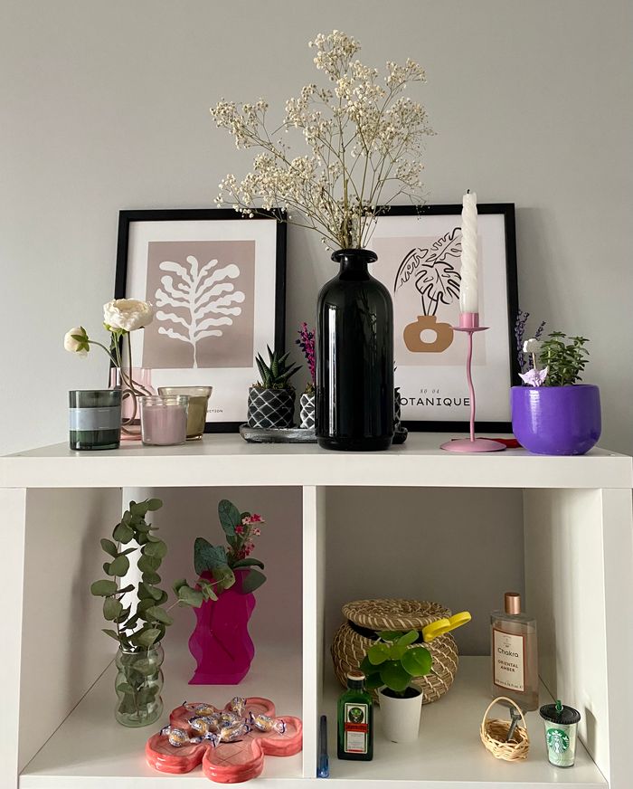 A stylish modern shelf featuring vases, plants, and artistic framed prints for interior decoration.