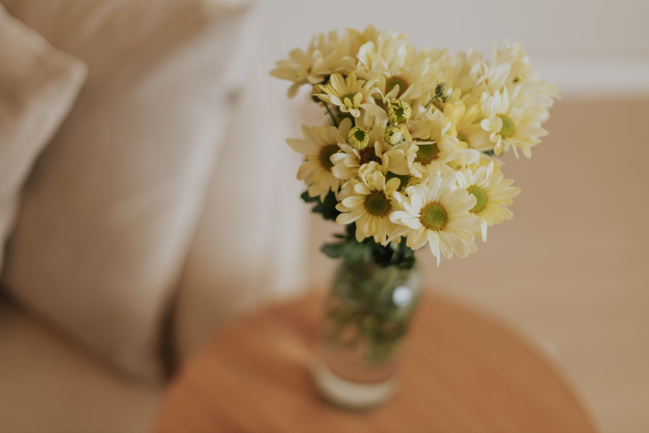 A serene arrangement of yellow daisies in a vase, perfect for minimalist interiors.